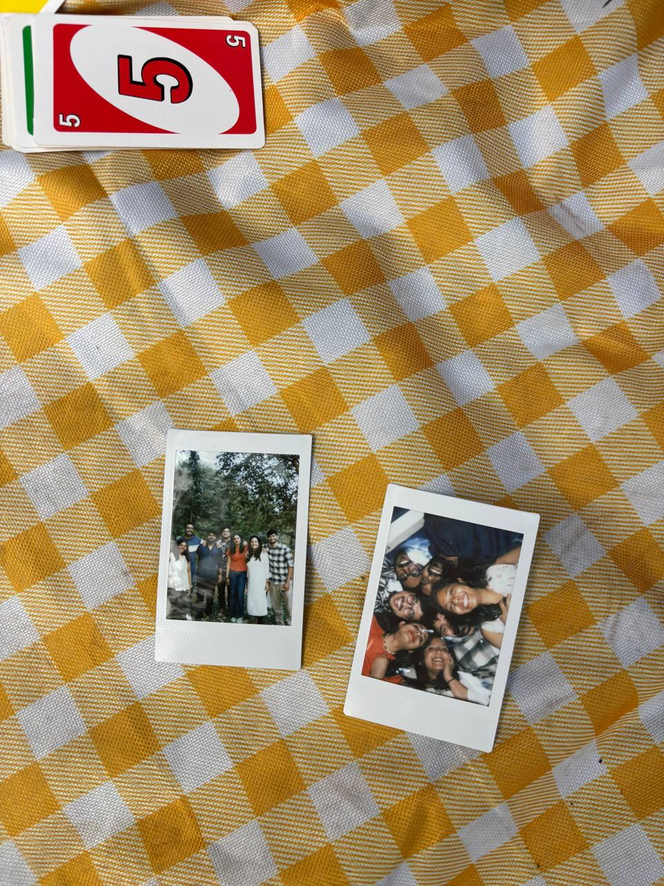 Uno cards and Polaroid photos on a yellow checkered tablecloth